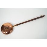 A copper hot water warming pan, set with a central screw out plug on a turned wood handle,