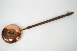 A copper hot water warming pan, set with a central screw out plug on a turned wood handle,