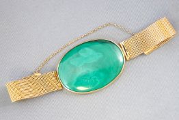 A yellow metal strap bracelet having a central large oval cabochon malachite