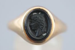 A yellow metal oval signet ring with carved cameo style onyx. Hallmarked 9ct gold, London, 1972.