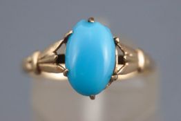 A yellow metal single stone ring set with a cabochon cut commercial turquoise.