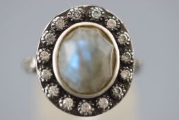 A satin finish white metal cluster ring set with a faceted cut oval labradorite