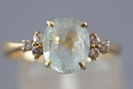 A yellow metal dress ring set with an oval faceted cut aquamarine