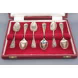 A cased set of six white metal (marks indistinct), Old English picture back tea spoons,
