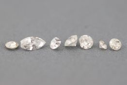 A collection of seven loose diamonds. Six are round brilliant cut and one is pear faceted cut.