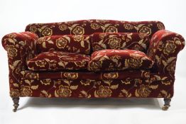 An Edwardian drop end two seat sofa on turned legs with brass casters,