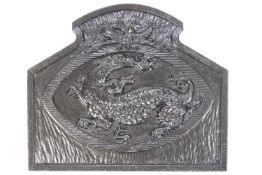 A cast iron fireback with a dragon within a cartouche painted within,