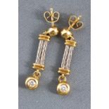 A yellow and white metal pair of drop earrings.