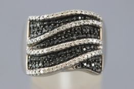 A white metal dress ring pave set with black and white single cut diamonds.