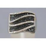 A white metal dress ring pave set with black and white single cut diamonds.