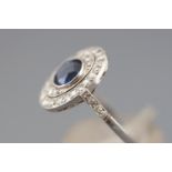 A white metal cluster ring set with a central deep blue sapphire