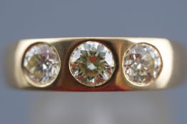 A yellow metal ring set with three round brilliant cut diamonds