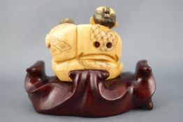 A late 19th century ivory netsuke of an old couple, seen seated and embracing,
