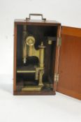 A brass microscope, by Watson & Sons, stamped, with swing handle,