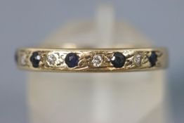 A yellow metal half hoop ring set with sapphires and single cut diamonds.