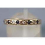 A yellow metal half hoop ring set with sapphires and single cut diamonds.