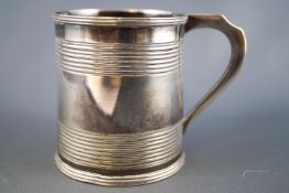 A silver mug,of small plain form, with ribbed lip and applied strap handle,