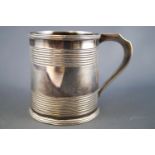 A silver mug,of small plain form, with ribbed lip and applied strap handle,