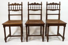 A set of six French oak dining chairs with caned seats on turned and fluted legs,