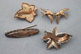 A collection of four silver and 9ct gold brooches of variable designs.