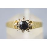 A yellow and white metal cluster ring. Set with a central sapphire.