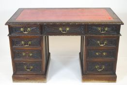 A Victorian carved oak pedestal desk with leather inset top above three frieze drawers