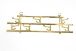 A brass hanging coat hook array with seven folding coat hooks in two rows,