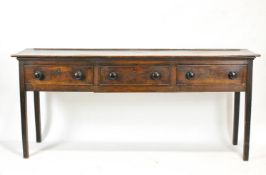 A George III oak dresser base, the three frieze drawers with later turned handles on square legs,