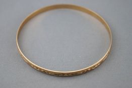 A yellow metal slave bangle with diamond cut leaf design. 65.0mm diameter; 4.5mm width.