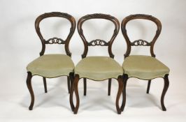 A set of six Victorian mahogany balloon back chairs with flower carved crests,