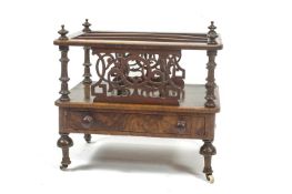 A Victorian walnut Canterbury with one frieze drawer on turned legs and casters,