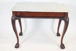 A marble topped centre table in George III style with carved cabriole legs with ball and claw feet,