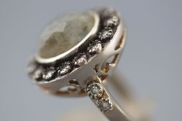 A satin finish white metal cluster ring set with a faceted cut oval labradorite