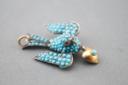 A yellow metal bird pendant set with cabochon cut turquoise and finished with cabochon ruby eyes.
