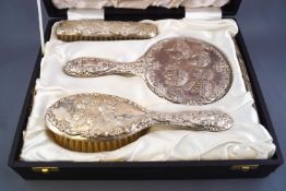 A cased silver four piece dressing table set, comprising two brushes, a hand mirror and comb,