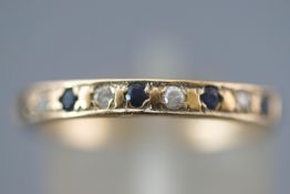 A yellow metal half hoop ring set with round faceted cut sapphire and cubic zirconia.