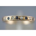 A yellow metal half hoop ring set with round faceted cut sapphire and cubic zirconia.