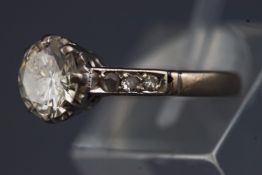 A white metal diamond ring set with a single round brilliant cut diamond