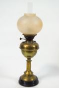 A brass oil lamp with frosted glass globular shade,