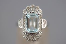 A white metal cluster ring set with a principal rectangular faceted cut aquamarine