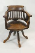 A mahogany swivel office chair with bow back, solid shaped seat and four splayed legs,