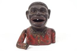 A cast iron money box in the form of a negro that feeds himself coins,