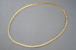 A yellow metal collar necklace with Greek key design.