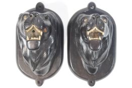 A pair of ebony lions heads, 3d carved in a snarling pose,