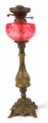 A gilt metal oil lamp with cranberry tinted glass reservoir,