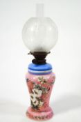 A Victorian opaline glass oil lamp, painted with flowers on a pink ground,