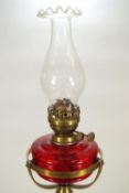 A brass and mahogany standard oil lamp with a red glass reservoir oil lamp on an extending pole