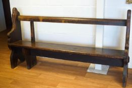 A 19th century pine pew with rail back and shaped ends raised on three feet with Gothic/Ogee cut