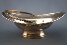 A silver small scale swing handled cake basket, of oval form, with applied reeded edge,