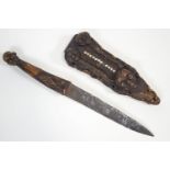 A Congolese knife, in wood and iron, the handle with a male mask finial,